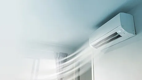 Wall-mounted split system blowing cool air into a bright room